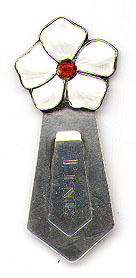 This bookmark was made in Norway. It is marked 830S with an H hallmark. The top is a figural flower with white enamel petals and a red enamel center. The front is inscribed "Tine". The date is 1920 - 1930.