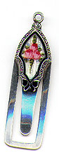 This bookmark was made in the US by an unknown manufacturer. It is marked with the makers mark and sterling. The top is an enamel picture of pink flowers The date is 1900 - 1910.