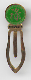 This bookmark was made in China. It is made of tin and enamel paint and is green with a Chinese symbol on the top. Written underneath the symbol is "Prosperity". The date is 1970 - 1980.  