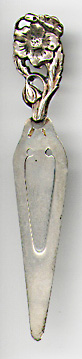 This bookmark is made in Holland. It is marked with the symbol for Holland of a sword and M140C. It is sterling and has a figural flower, bud and leaf on top. The date is 1920 - 1930.