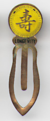 This bookmark was made in China. It is made of tin and enamel paint and is yellow with a Chinese symbol on the top. Written underneath the symbol is "Longevity". The date is 1970 - 1980.  
