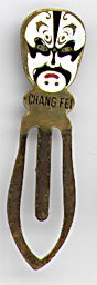 This bookmark was made in China. It is made of tin and enamel paint and has a white blue and pink Chinese mask on top. Underneath the mask is written "Chang Fei". The date is 1970 - 1980.  
