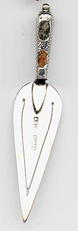This bookmark was made in England. It has the marks for Birmingham, 1908. It is a figural trowel with two different colored stones in the handle. 