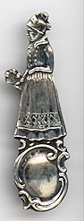 This bookmark was made in Holland. It is marked 830S. It is a figural woman in a dress carrying some flowers. The date is 1890 - 1900.