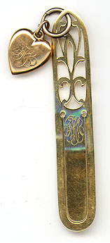 This bookmark was made in the US by Gorham. It is marked with the makers hallmark and 14K and the number X1154. It is a deco design with an attached heart charm. The date is 1910 to 1920.