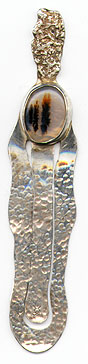 This bookmark was made in the US by an unknown manufacturer. It is marked Sterling on the back and has an unknown mark on the bottom of the middle blade. It is handmade with a hand hammered finish. The top has a brown and white agate stone. The date is 1920 - 1940.