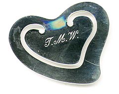 This bookmark was made in the US by Tiffany and Co. It is marked with the makers hallmark and a signature of the artist who designed it. It is in the shape of a fancy heart. The date is 1980 - 1990.