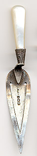 This bookmark was made in Birmingham, England by Addie and Lovekind in 1902. It is marked with the hallmarks for that date and place. It is in the shape of a trowel with a mother of pearl handle.