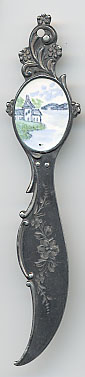  This bookmark was made in the US by an unknown manufacturer. It is only marked sterling on the back. The top has an enamel medalion with a scene of house on the edge of a body of water with mountains in the background. The date is 1900 - 1910.  