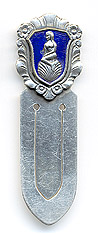 This bookmark was made in Denmark by Meka. It is marked Meka Sterling Denmark on the back. The top is a rectangular medallion surrounded by flowery motif. The medallion is a picture of a mermaid sitting on a shell surrounded in a blue enamel. The date is 1930 - 1960.