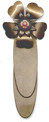  This bookmark was made in the US by an unknown manufacturer. It is made of brass and has some glass beads. It is in the shape of a flower with brass petals and glass beads in the center.  