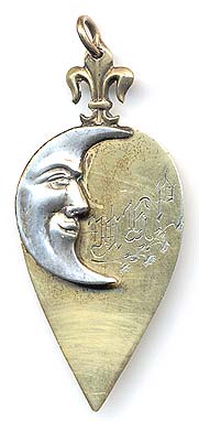  This bookmark was made in the US by an unknown manufacturer. It is marked sterling 5005 on the back. This is a two-toned silver bookmark where the top blade is a figural man in the moon in white silver and the bottom blade is finished in a gold wash in the shape of a spade. The top has a fleur-de-lis. The date is 1892.   