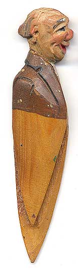  This bookmark was made in Italy by the Anri workshop. It is carved of wood and depicts a bald man in a brown suit. 