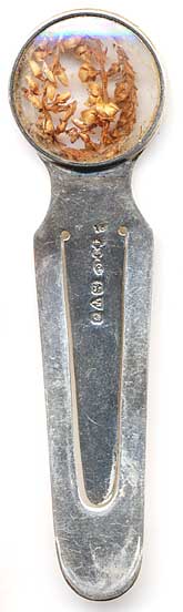 This bookmark is made in Chester, England. The manufacturer's mark is S.M. & Co. for Sampson Mordan & Co. The top contains a dried out plant with seeds. The date is 1914 - 1915.