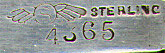 This bookmark was made in the US by Shiebler. It is marked with the manufacturers hallmark and the number 4365. It is in the shape of a ribbon with a bow at the top. The date is 1890 - 1900. 