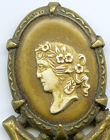 This bookmark was made in France. It is unmarked gilded brass and has a cameo on top. The date is 1890 - 1910.