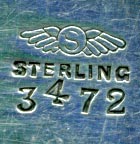 This bookmark was made in the US by Shiebler. It is marked with the makers hallmark of a winged letter S and sterling. The top is an ornate 3D design and an angel/cherub forms the top blade of the bookmark.