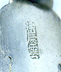 This bookmark was made in China and is hallmarked with Chinese symbols. It is in the shape of a trowel with a dragon as the handle.