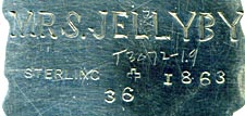 This bookmark was made in the US by J.F. Fradley. It is marked on the back with sterling, the manufacturers hallmark of a cross, the numbers 1863 and 36, and Mrs. Jellyby. This is a figure of the Dickens character from the book "Bleak House." The date is 1890 - 1936.