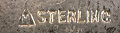 This bookmark was made in the US by F. A. Herman. It is marked with a hallmark of a triangle enclosing the letter H and sterling. The top is a cyan and black enamel shield. The date is 1900 - 1910.