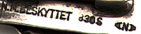 This bookmark is from Norway. It is marked N.M. BESKYTTET 830S  A N A (two horizontal A's) NORDLIE, ARNE EMANUEL  1908 - 1995 OSLO.NM stands for Norsk Mønster (Norwegian pattern) Beskyttet (protected) started using after 1929. It is a very unusual piece. The smaller part clips onto a page where the connecting bar swings to let the longer part hang over the front or back cover of the book. 