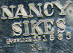 This bookmark was made in the US by J. F. Fradley & Co. It is marked "Nancy Sikes", the manufacturers hallmark, Sterling, number 1863 and number 11. It is in the shape of a woman with the smaller blade as the sleeve of the woman's dress. This is part of a series of bookmarks from Dickens novels. The date is 1890 - 1936.