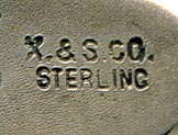 This bookmark was made in the US by an unknown manufacturer. It is marked X&S Co. Sterling on the back. This is a tiny bookmark with the top blade a floral art nouveau shape. The date is 1900 - 1910.  