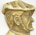 This bookmark was made by an unknown manufacturer. It is ivory or bone and has a hand carved highly detailed side view of a man's head  wearing a cap on top. The date is 1900 - 1910.