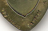 This bookmark was made in the US by Gorham. It is marked with the Gorham hallmarks and B1573M and the date mark for 1898. It is a heart shaped bookmark with a cherub on top finished in a gold wash. The original tassel is attached on top.