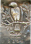 This bookmark was made in the US by Shiebler. It is marked with the Sheibler hallmark, sterling and 2099. The top is a relief picture of a bird perched on a branch. The reverse side has another view of the bird. The blades are hand hammered. The date is 1900 - 1910.