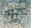 This bookmark was made in the US by Gorham. It is marked sterling, the hallmark for Gorham, 1569M and the date mark for 1887. The top is a figural crown with two leaves underneath it which are used as the top blade.