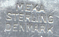 This bookmark was made in Denmark by Meka. It is marked Meka Sterling Denmark on the back. The top is a rectangular medallion surrounded by flowery motif. The medallion is a picture of the island of St. Thomas in the Virgin Islands in a blue enamel. The date is 1930 - 1960.