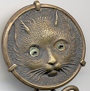  This bookmark was made in France. It is brass and the top is a relief picture of a kitty with light green glass eyes. The date is 1890 - 1910.  