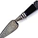 This bookmark is made in England. It is shaped like a trowel and has a Jet handle. The blade has a flowery design. There are no hallmarks.