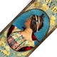 This bookmark was made in the US as an advertisement for St. Raphael wine. It is painted tin and has a picture of a woman in the center.
