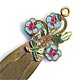 This bookmark is made of brass with enamel flowers on top. The manufacturer is unknown.