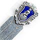 This bookmark was made in Denmark by Meka. It is marked Meka Sterling Denmark on the back. The top is a rectangular medallion surrounded by flowery motif. The medallion is a picture of a mermaid sitting on a shell surrounded in a blue enamel. The date is 1930 - 1960.