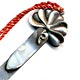This bookmark is made in the US by an unknown manufacturer. It is marked Solid Silver on the back. The top is a figural flower with a stem and a long red tassel. The date is 1920 - 1950.